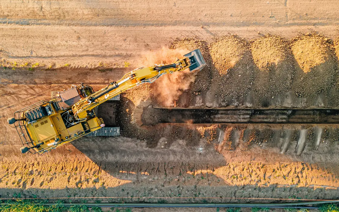 Excavator digging a pipeline trench, seen from above