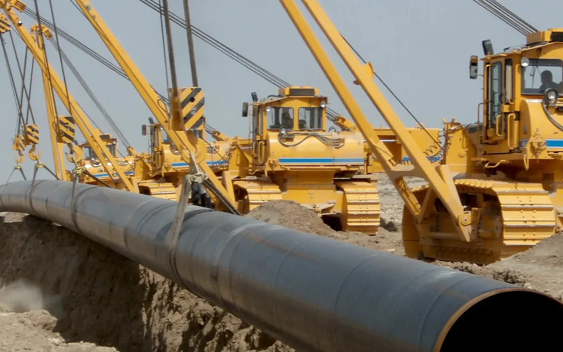 Pipe layers (side booms) lowering a welded steel pipeline into the trench